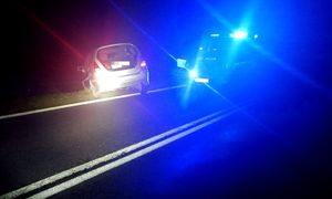 radiowóz na drodze, obok pojazd osobowy przy skrapie