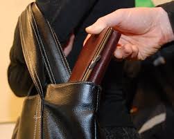 zdjęcie poglądowe ktoś wyjmuje portfel z zawieszonej na ramieniu torebki