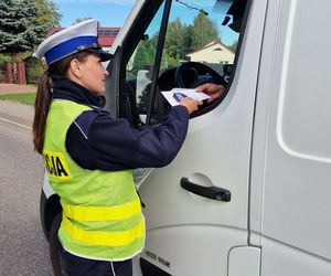 policjantka w kamizelce odblaskowej wręczająca kierowcy ulotkę