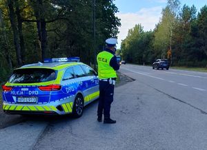 policjant przy radiowozie z miernikiem prędkości