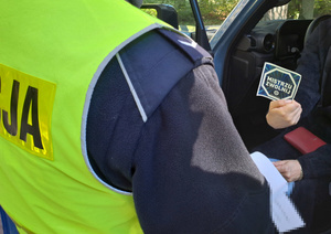 kierowca trzyma w reku ulotkę Mistrzu Zwolnij