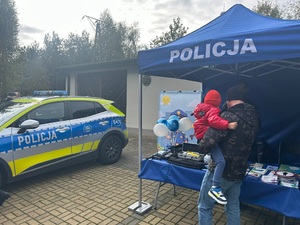 mężczyzna trzymający dziecko na rękach stoi przy stoisku policyjnym