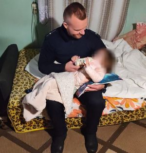policjant karmi małą dziewczynkę mlekiem z butelki