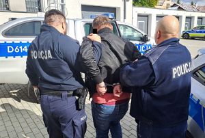 policjanci prowadzą zatrzymanego mężczyznę
