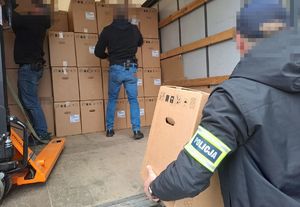 policjanci pakują na samochód ciężarowy zabezpieczone ekspresy w pudełkach