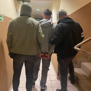 policjanci prowadzą zatrzymanego mężczyznę