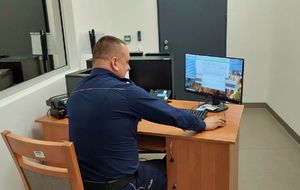 umundurowany policjant siedzi przy biurku przed komputerem