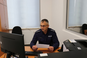 umundurowany policjant siedzi przy biurku przed komputerem