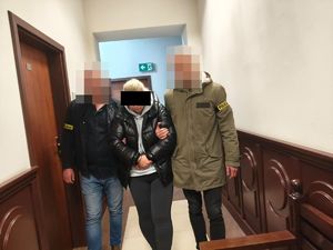 policjanci prowadzą zatrzymaną kobietę
