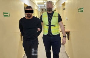 policjant prowadzi zatrzymanego mężczyznę