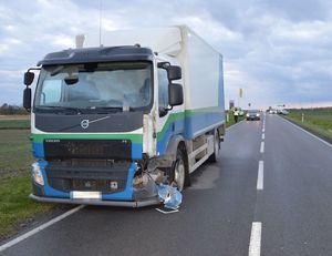 uszkodzony pojazd ciężarowy na drodze, w tle policjant radiowozy i inne pojazdy