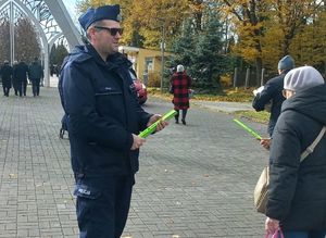 policjant rozdaje odblaski pod cmentarzem