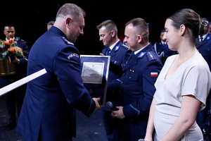 Komendant inspektor Tomasz Gil wręcza podziękowanie aspirantowi Pawłowi Cieliczko.