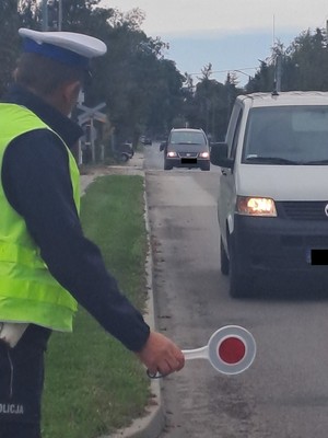 policjant zatrzymuje tarczą pojazd do kontroli