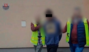 policjanci kryminalni prowadzą zatrzymanego 25-latka