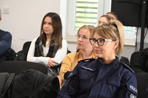 policjantka i studenci siedzą na krzesłach