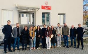 przed budynkiem Ośrodka Szkolenia Policji stoją studenci i policjanci