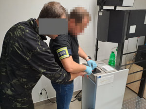 Policjant pobiera odbitki palców na urządzeniu elektronicznym od zatrzymanego mężczyzny