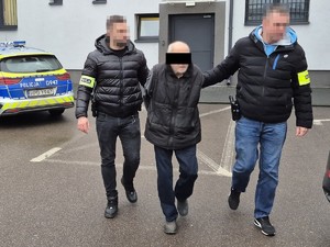 policjanci prowadzą zatrzymanego 73-latka