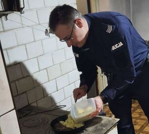 policjant przygotowujący posiłek na kuchni węglowej