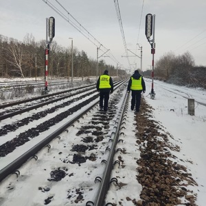funkcjonariusze policji  patrolują i sprawdzają teren linii kolejowej