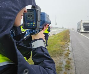 Na zewnątrz przy drodze trwa kurs specjalistyczny z obsługi ręcznych mierników prędkości