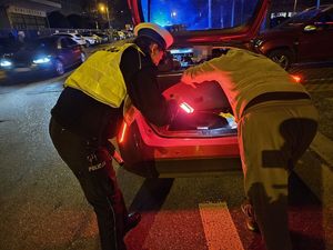 Policjantka sprawdza w bagażniku wyposażenie taksówki.