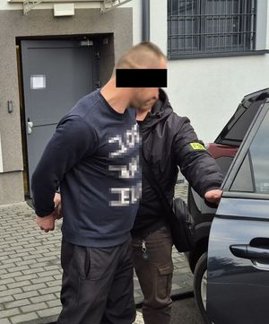 policjant prowadzi zatrzymanego do pojazdu