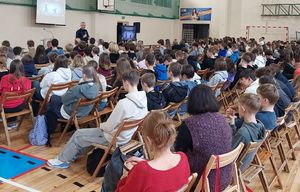 policjant podczas prelekcji z młodzieżą szkolną na sali gimnastycznej