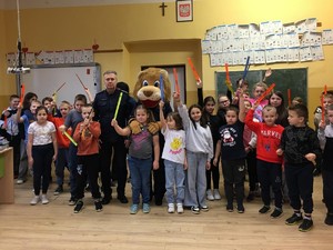 umundurowany policjant stoi w grupie uczniów