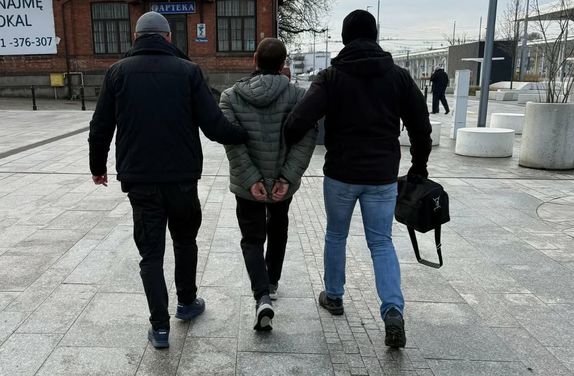 policjanci po cywilnemu prowadzą zatrzymanego poszukiwanego