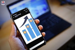 trzymany w ręku smartfon z grafiką inwestycji