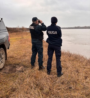 Wspólne działania Policji i Straży Rybackiej w rejonie Wisły. Strażnik spogląda przez lornetkę.