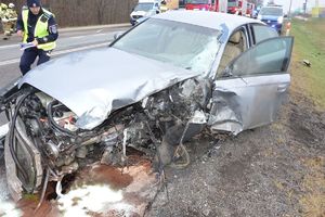 Zniszczony pojazd osobowy po zderzeniu z pojazdem ciężarowym. Policjant podczas oględzin
