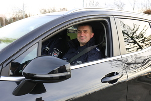 policjant siedzi za kierownicą nowego pojazdu marki Kia Sportage