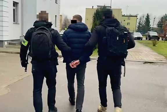sprawca pobicia doprowadzany przez policjantów kryminalnych