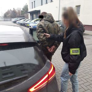 nieumundurowana policjantka prowadzi do samochodu zatrzymanego mężczyznę