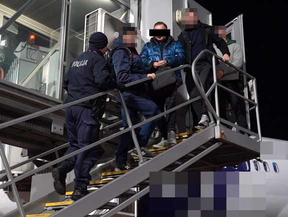policjanci wyprowadzają z samolotu poszukiwanego