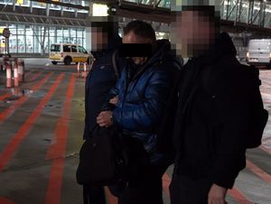 policjanci wyprowadzają z samolotu poszukiwanego