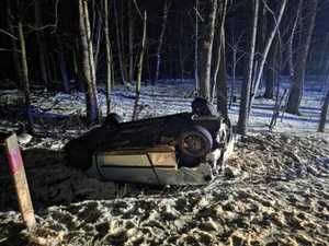 przewrócony na dach pojazd osobowy przy drzewach