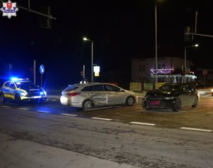 skrzyżowanie dróg, dwa samochody osobowe po zderzeniu, za nimi stoi policyjny radiowóz