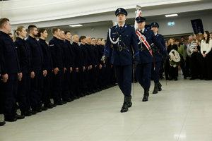Poczet Sztandarowy krokiem defiladowym wchodzi na salę w której odbywa się ślubowanie nowych policjantów.