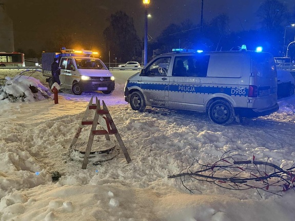 zabezpieczona studzienka, po prawej stronie radiowóz policyjny