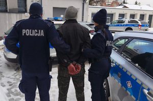 Policjanci prowadzą zatrzymanego mężczyznę.