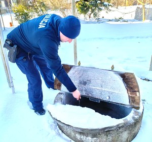 policjant przy studni pobiera wodę
