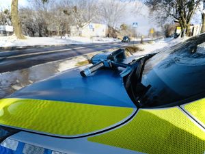 policyjny radiowóz przy drodze. Na nim leży miernik prędkości