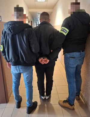 policjanci podczas doprowadzania zatrzymanego