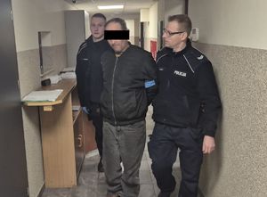 policjanci prowadzą korytarzem zatrzymanego 48-latka
