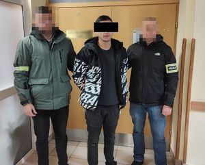 policjanci stoją przy zatrzymanym oszuście