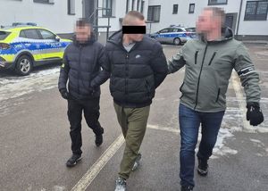 nieumundurowani policjanci prowadzą zatrzymanego